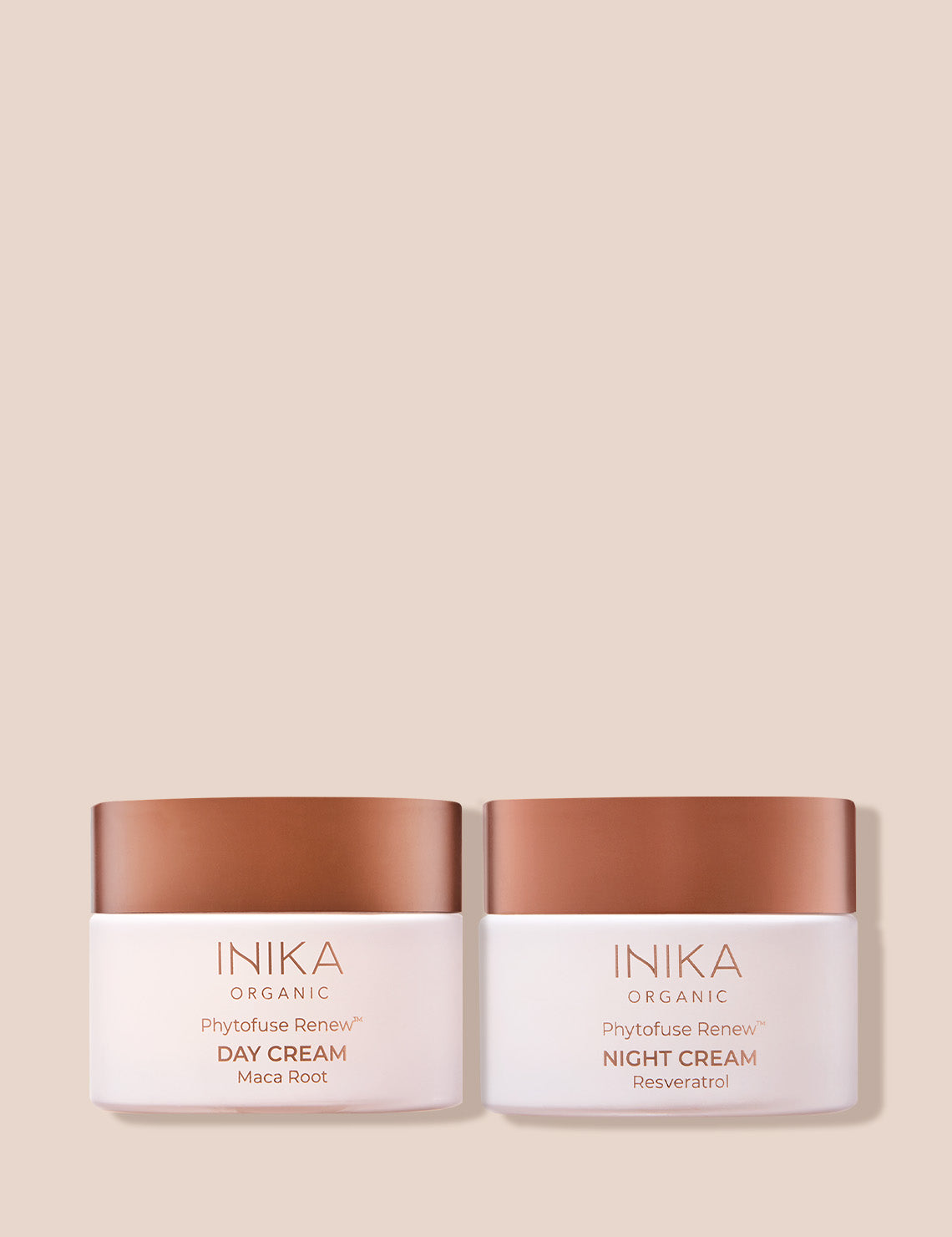 Inika Organic Phytofuse Renew Day and Night Creams with bronze lids against a beige background.