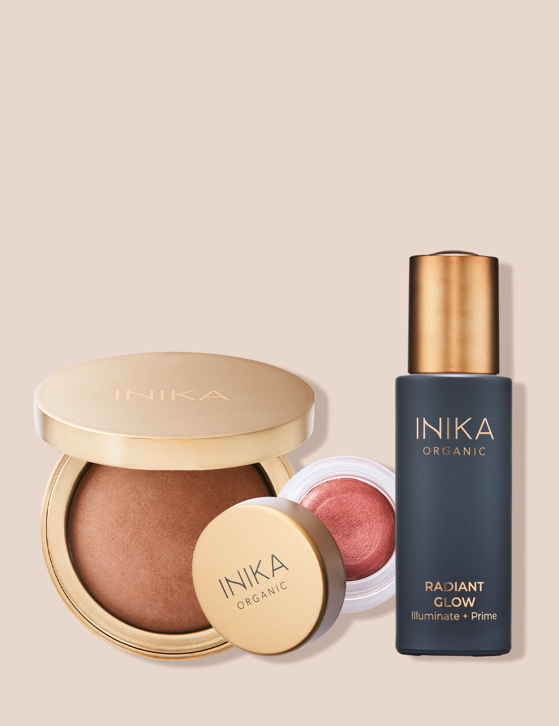 Inika cosmetics set with Radiant Glow primer, bronzer, and pink blush, featuring gold and black packaging against a beige background.